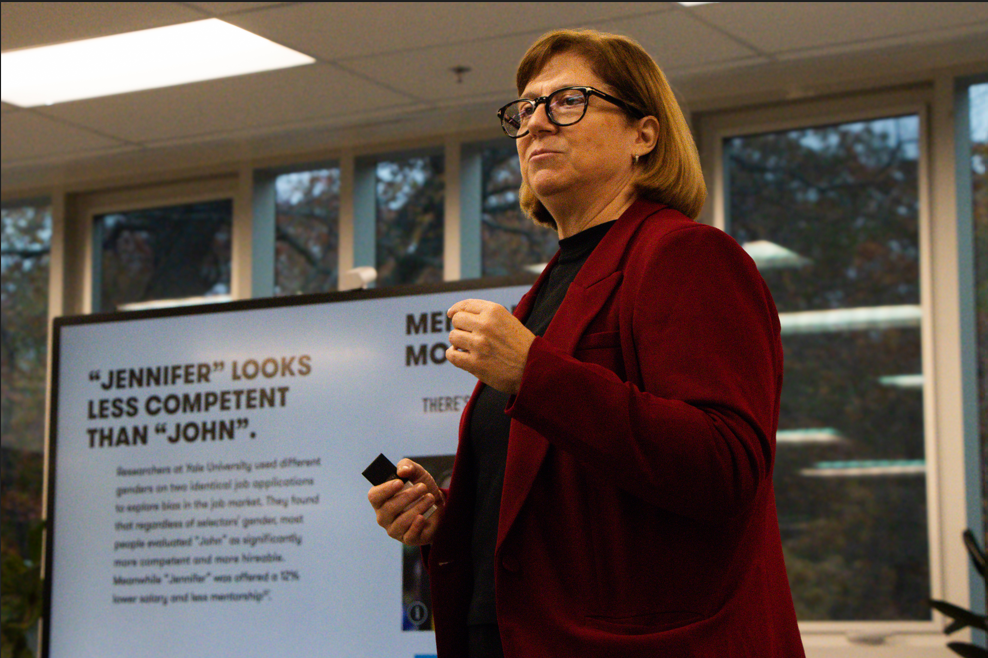a woman speaking in front of a powerpoint slide